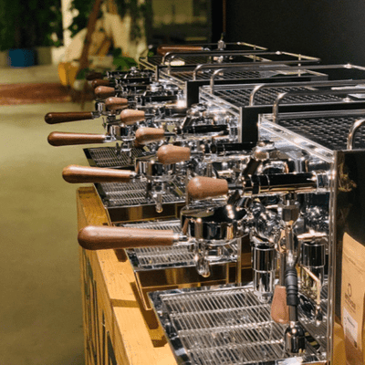 A row of MAKINA S7 Pro-PID espresso machines on a wooden counter